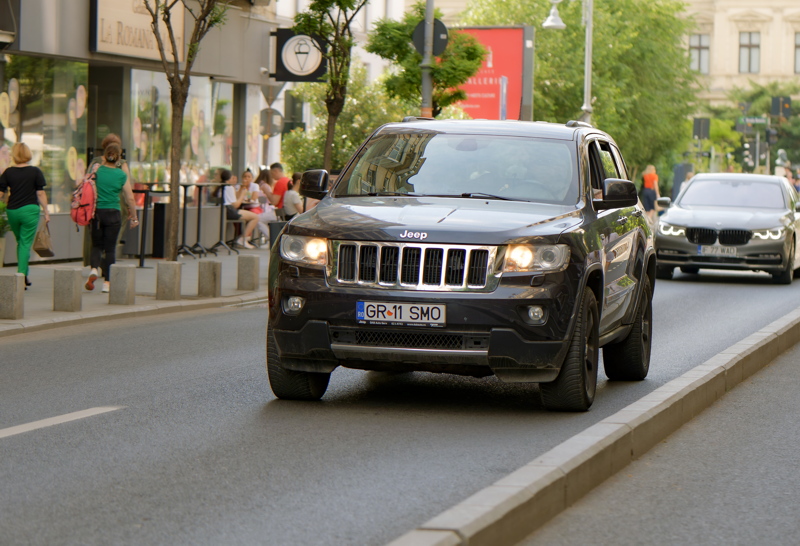 1 - A dark grey 2012 Jeep Grand Cherokee, a popular luxury SUV model, going on a street